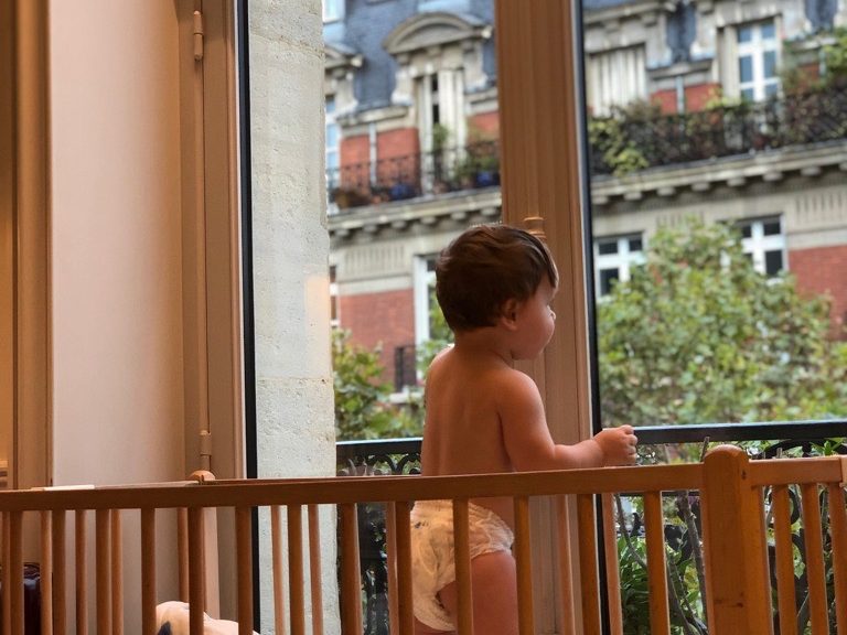 A toddler at the window of a Paris apartment