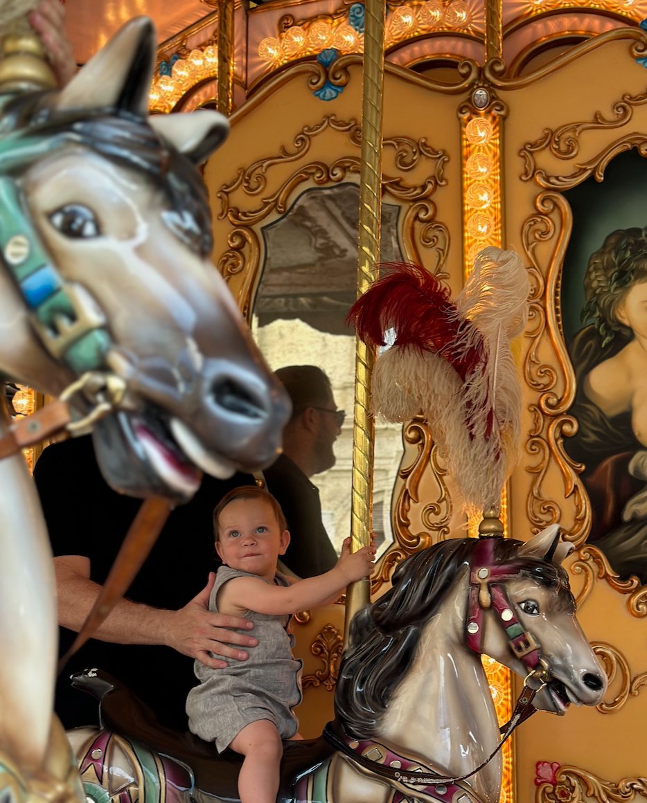 Baby on a Paris carousel held by their dad