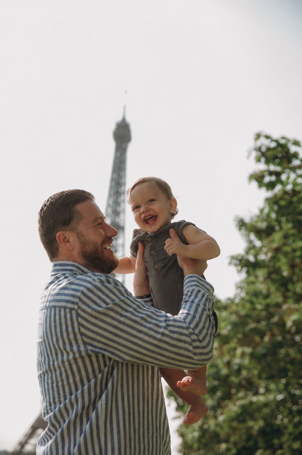 Father lifting laughing baby with the Eiffel Tower in the background
